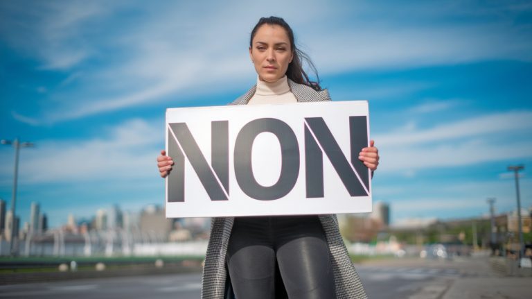 femme qui tient panneau avec écrit : NON