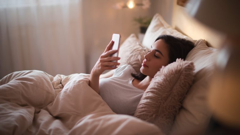 Femme dans le lit qui lis sur telephone